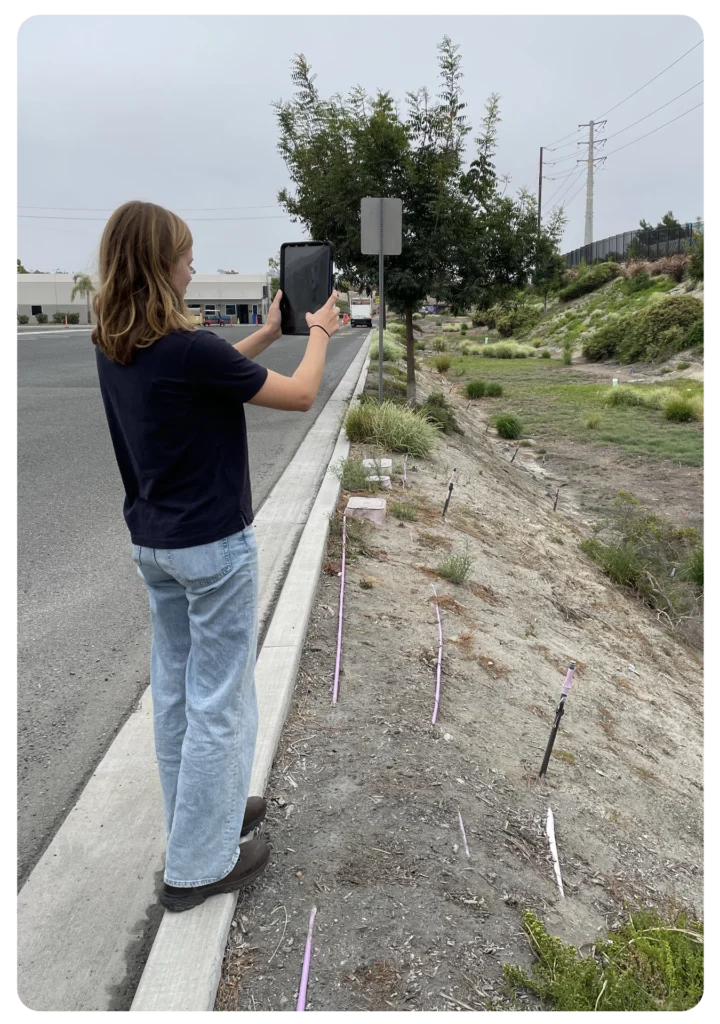 Oceanside staff member using an iPad to access 2NFORM during a field inspection of a stormwater BMP, demonstrating streamlined MS4 compliance and modern environmental management.